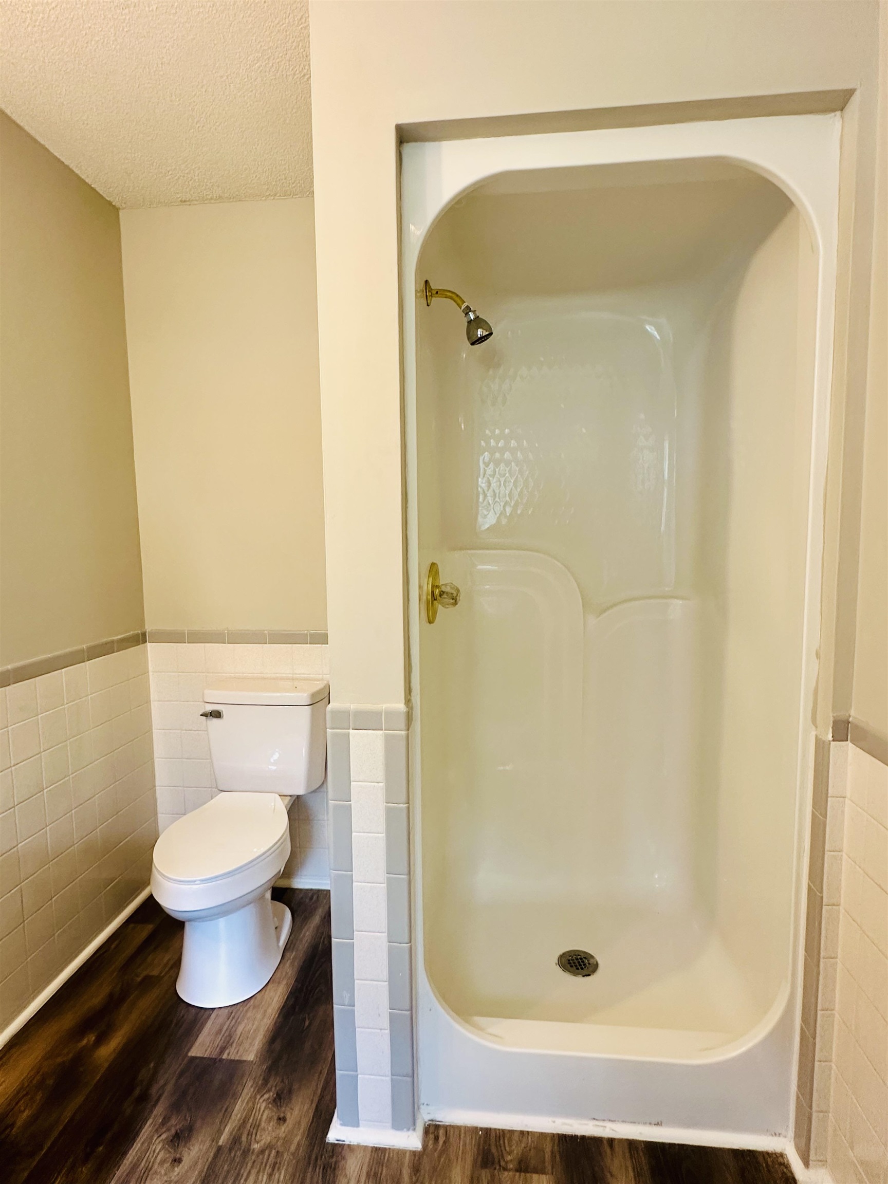 287 Gilchrist Stantonville Road Adamsville, TN 38310 - Photo 26 of 29 Full bathroom with wainscoting, tile walls, wood finished floors, a textured ceiling, and a walk in shower