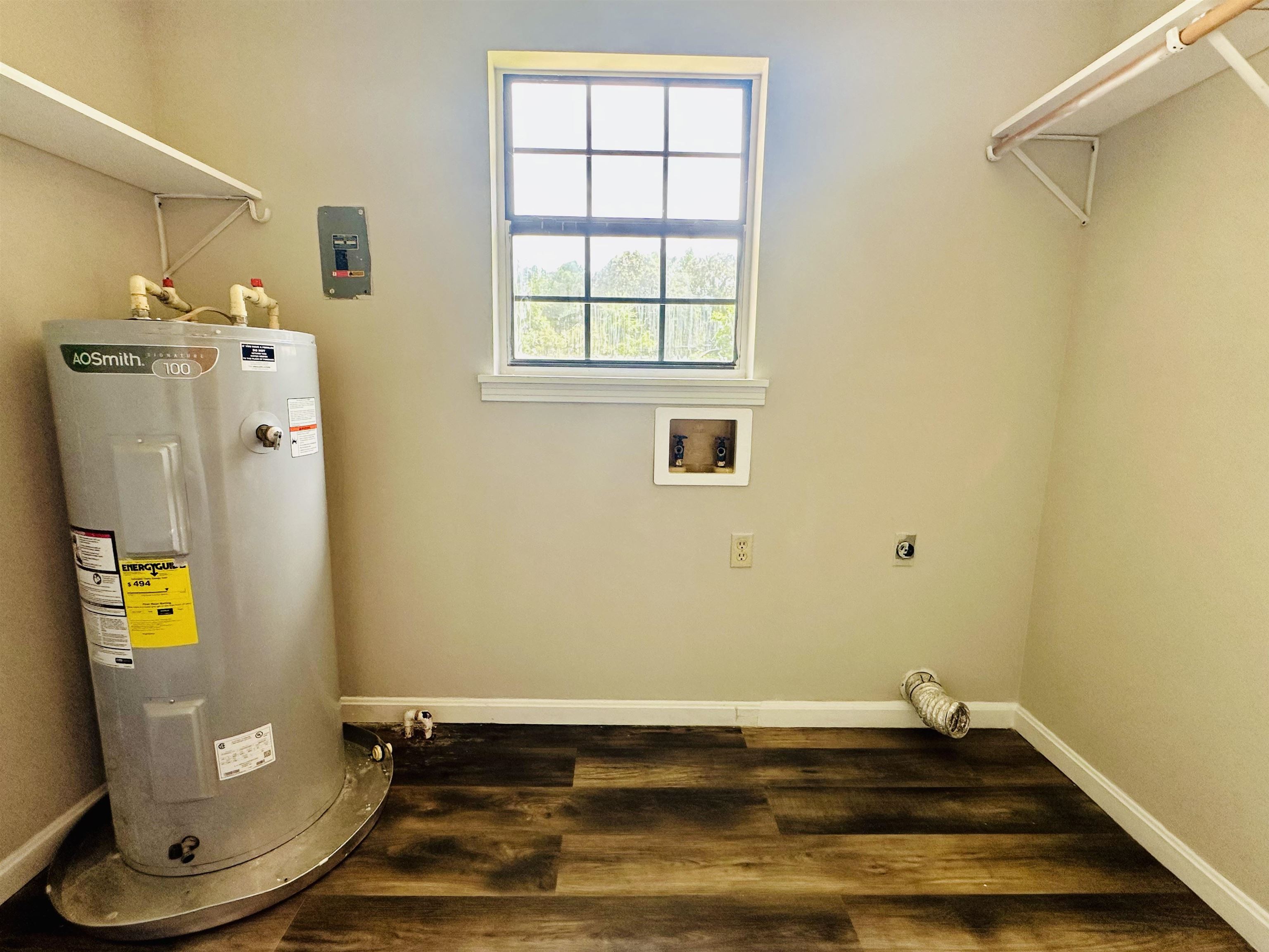 287 Gilchrist Stantonville Road Adamsville, TN 38310 - Photo 12 of 29 Laundry room with hookup for an electric dryer, water heater, washer hookup, and dark wood finished floors