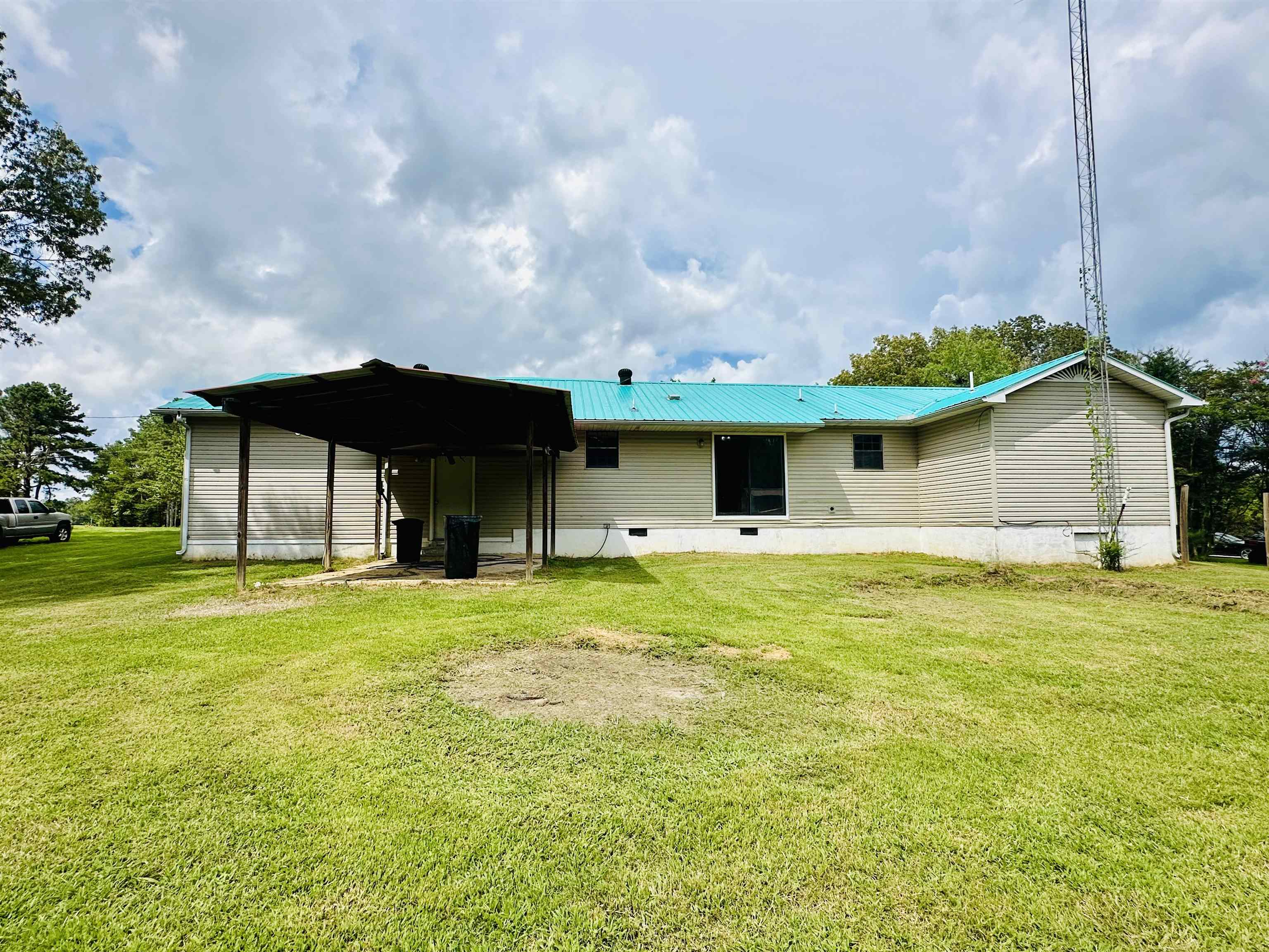 287 Gilchrist Stantonville Road Adamsville, TN 38310 - Photo 14 of 29 Rear view of house with crawl space, a lawn, a metal roof, and an attached carport