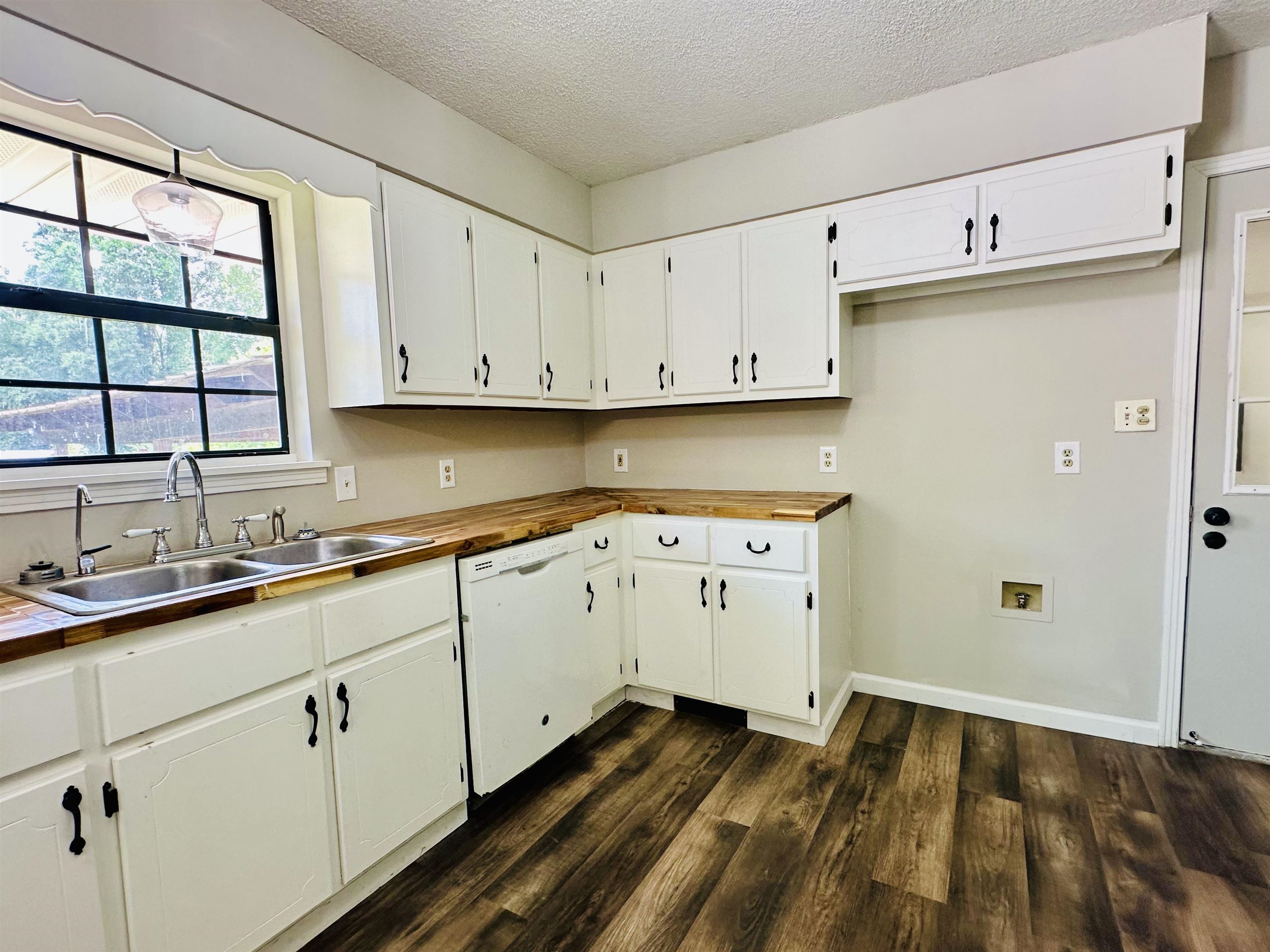 287 Gilchrist Stantonville Road Adamsville, TN 38310 - Photo 23 of 29 Kitchen with a textured ceiling, dark wood-style floors, dishwasher, white cabinetry, and butcher block counters