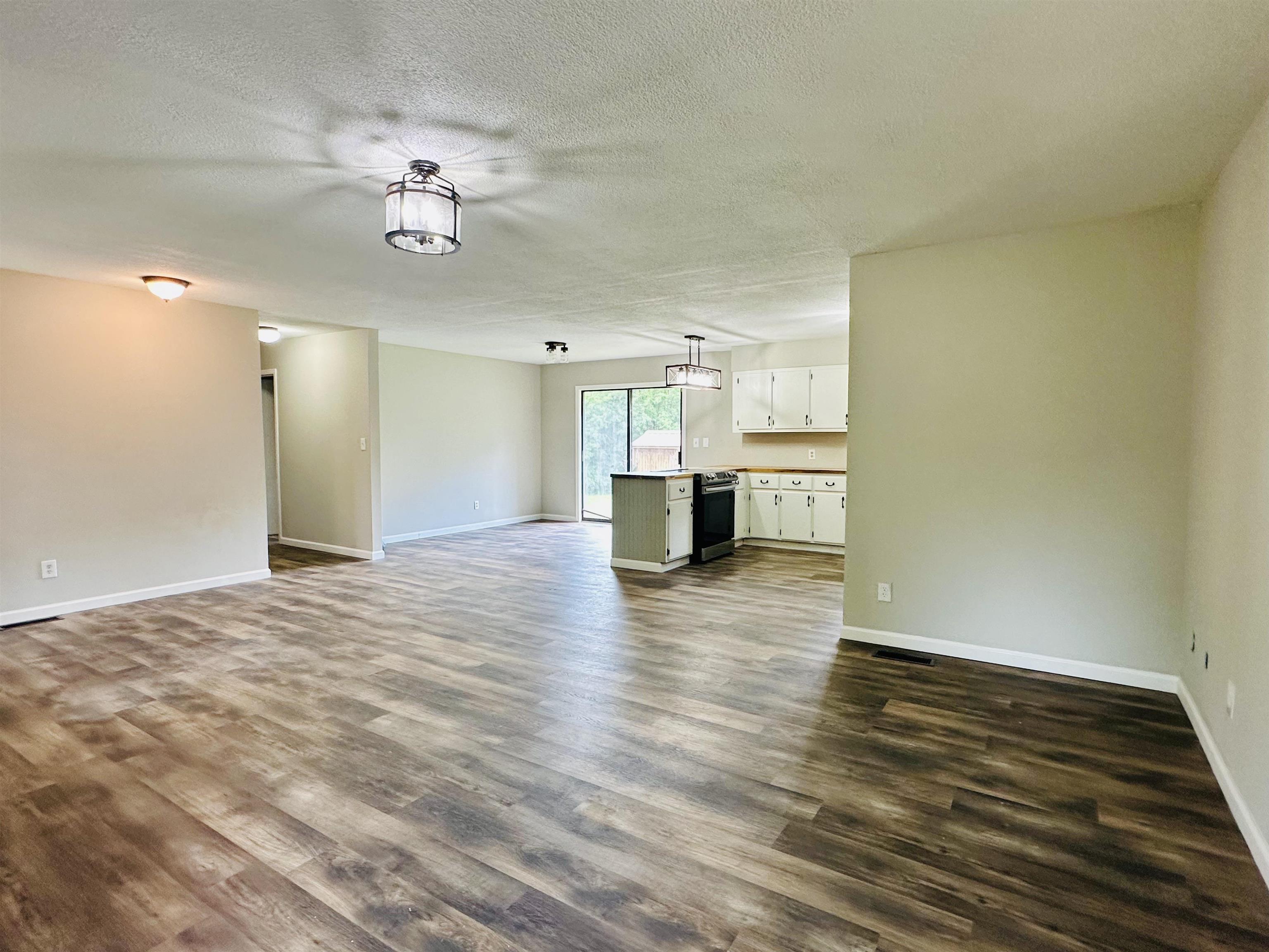 287 Gilchrist Stantonville Road Adamsville, TN 38310 - Photo 4 of 29 Unfurnished living room featuring dark wood-style flooring and a textured ceiling