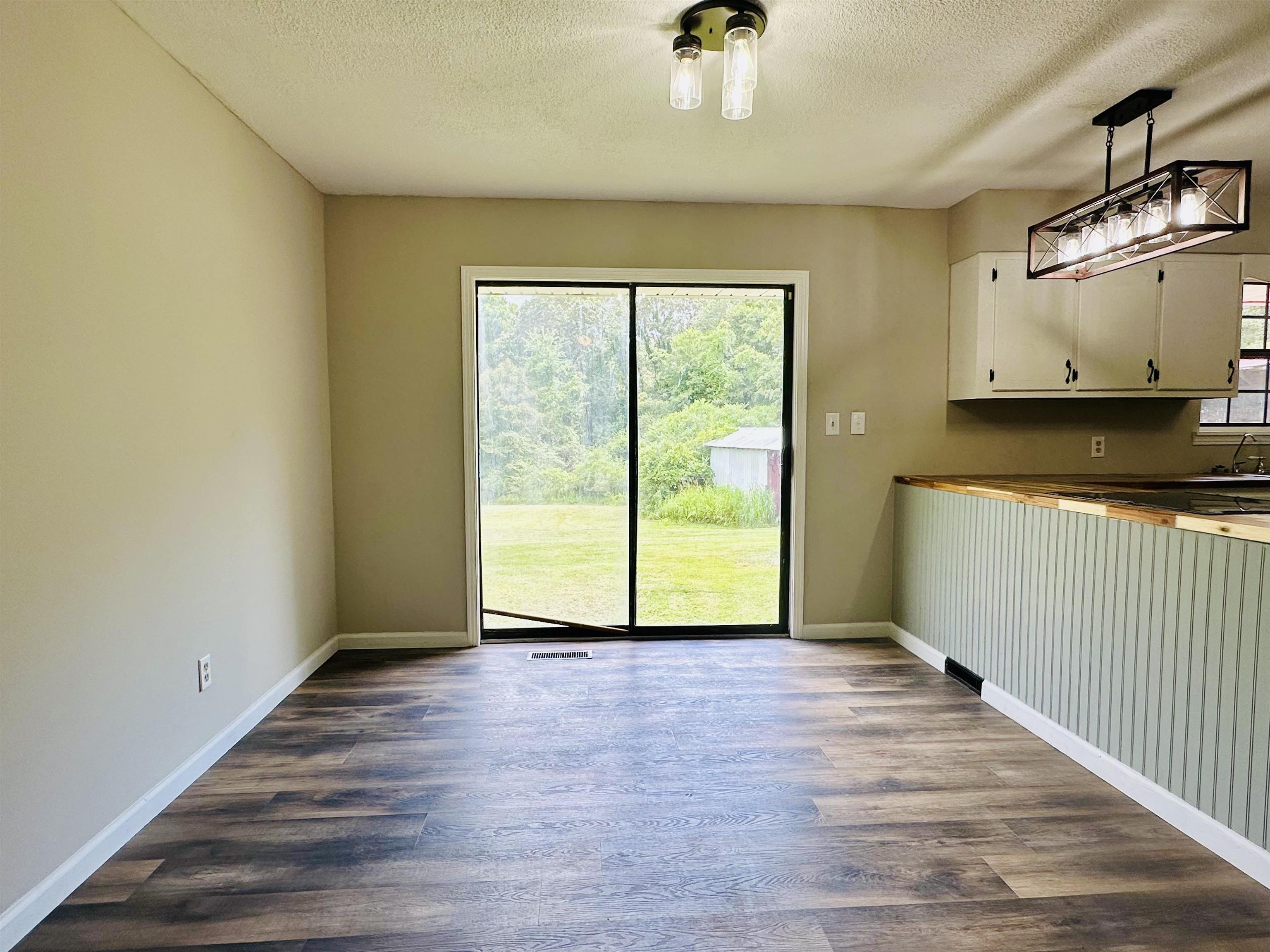 287 Gilchrist Stantonville Road Adamsville, TN 38310 - Photo 8 of 29 Unfurnished dining area with plenty of natural light, a textured ceiling, and dark wood-style flooring