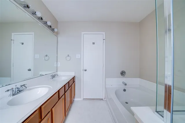 a bathroom with a tub double vanity sink and mirror
