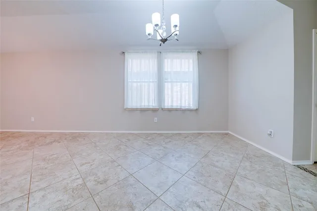 a view of an empty room with a chandelier fan