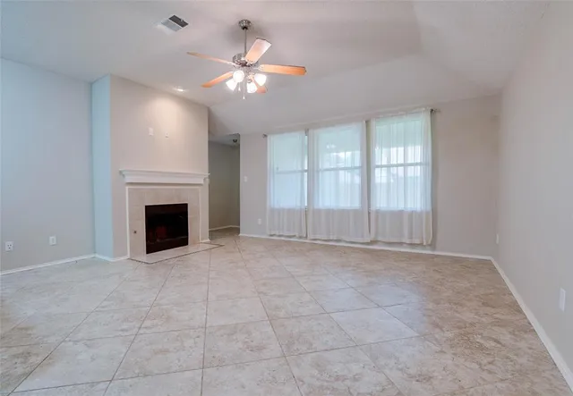 a view of an empty room with chandelier fan and fire place