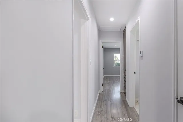 a view of a hallway with wooden floor and a bathroom