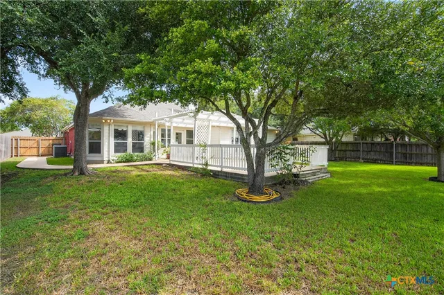 a white house that has a tree in front of a house