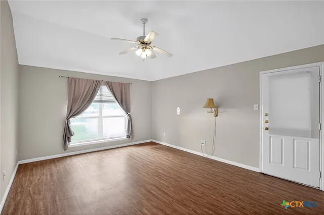 a view of empty room with wooden floor and fan