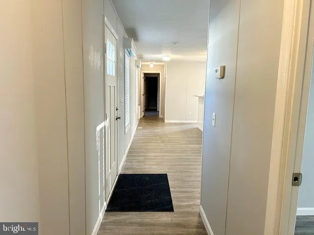 a view of a hallway with wooden floor and a bathroom