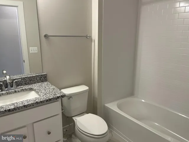 a bathroom with a granite countertop toilet sink and mirror