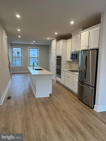 a kitchen with stainless steel appliances a refrigerator sink and wooden floor
