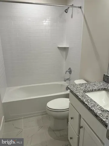 a bathroom with a granite countertop toilet and a shower