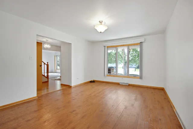 a view of an empty room with window and wooden floor
