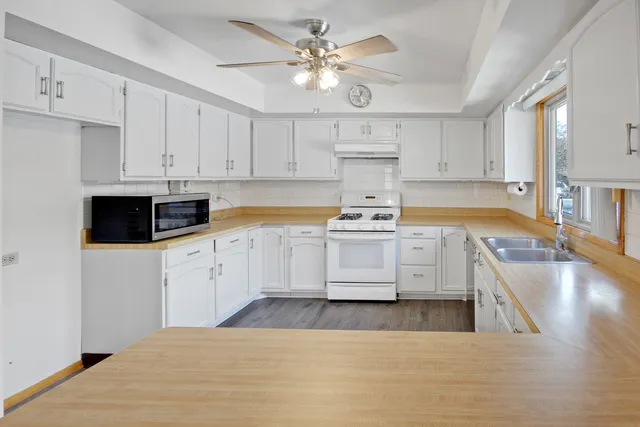 a kitchen with stainless steel appliances white cabinets a sink a stove a refrigerator and cabinets
