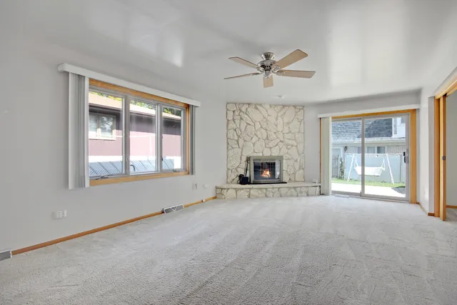 a view of an empty room with window and chandelier fan