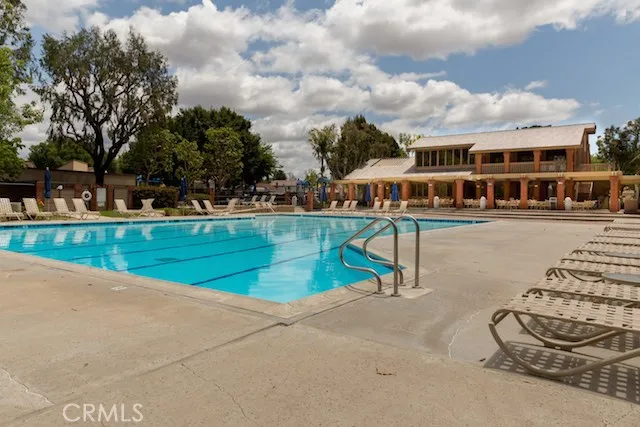 a view of swimming pool with outdoor seating and trees in the background