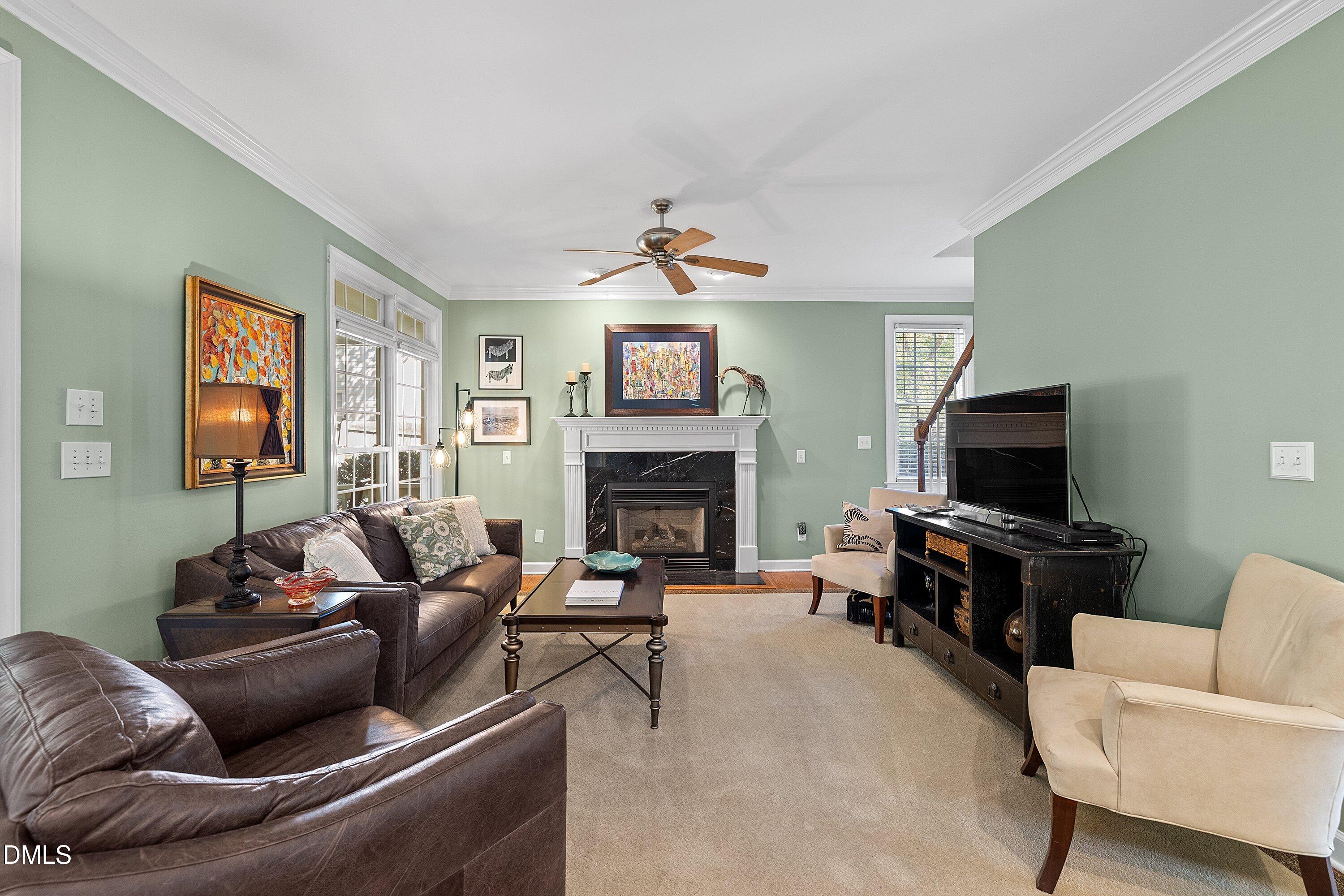 3914 Sterling Ridge Lane Durham, NC 27707 - Photo 15 of 66 Living area featuring a fireplace with a black surround, crown molding, and a ceiling fan