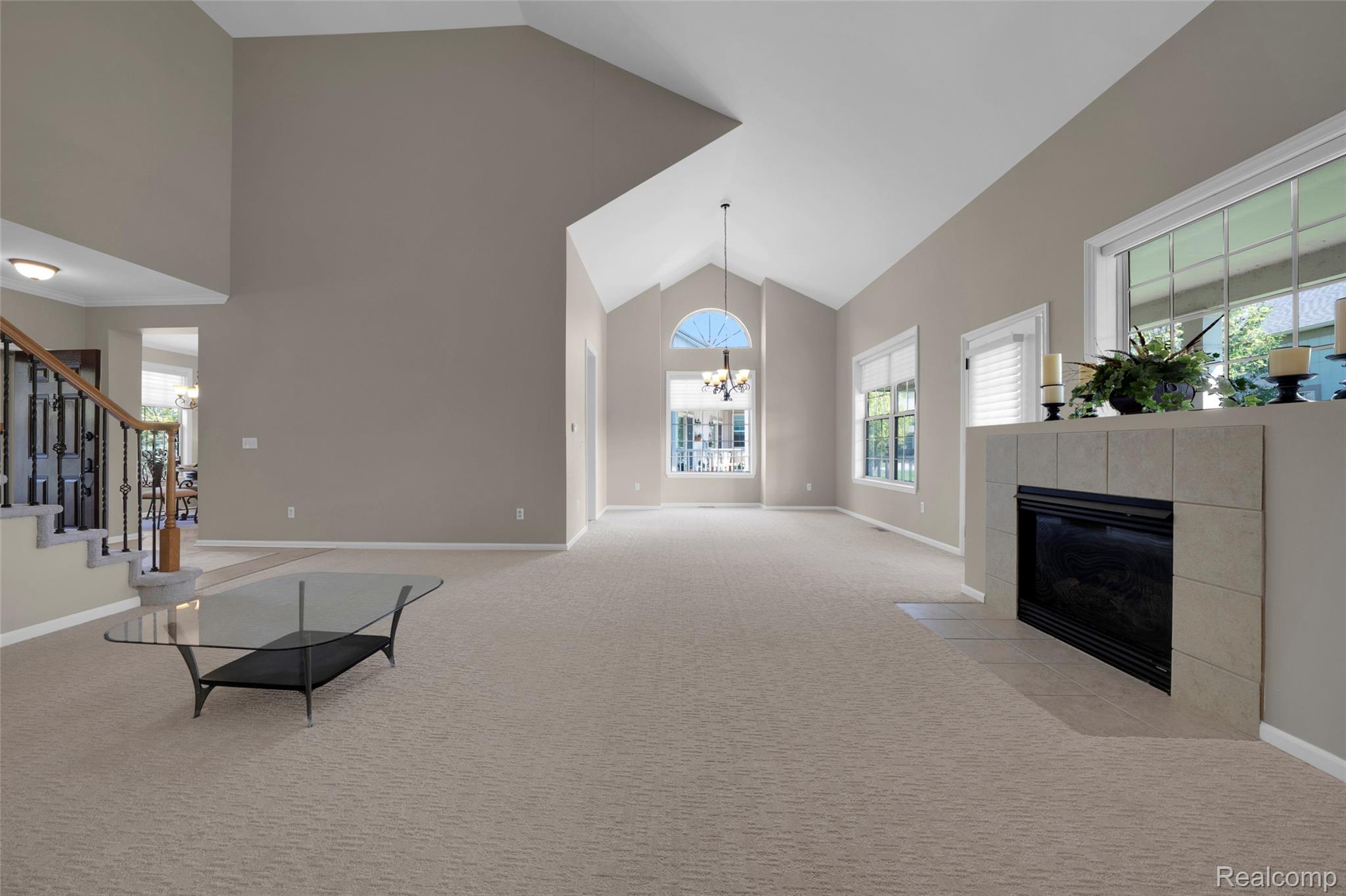 3805 Windingbrook Circle, Unit 22 Rochester, MI 48309 - Photo 20 of 63 Vaulted ceilings define this spacious room, featuring a carpeted floor, a tiled fireplace hearth, and multiple large windows for abundant natural light