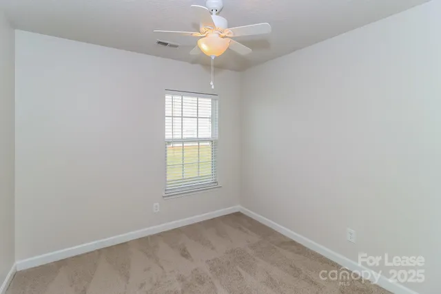 an empty room with a window and a fan
