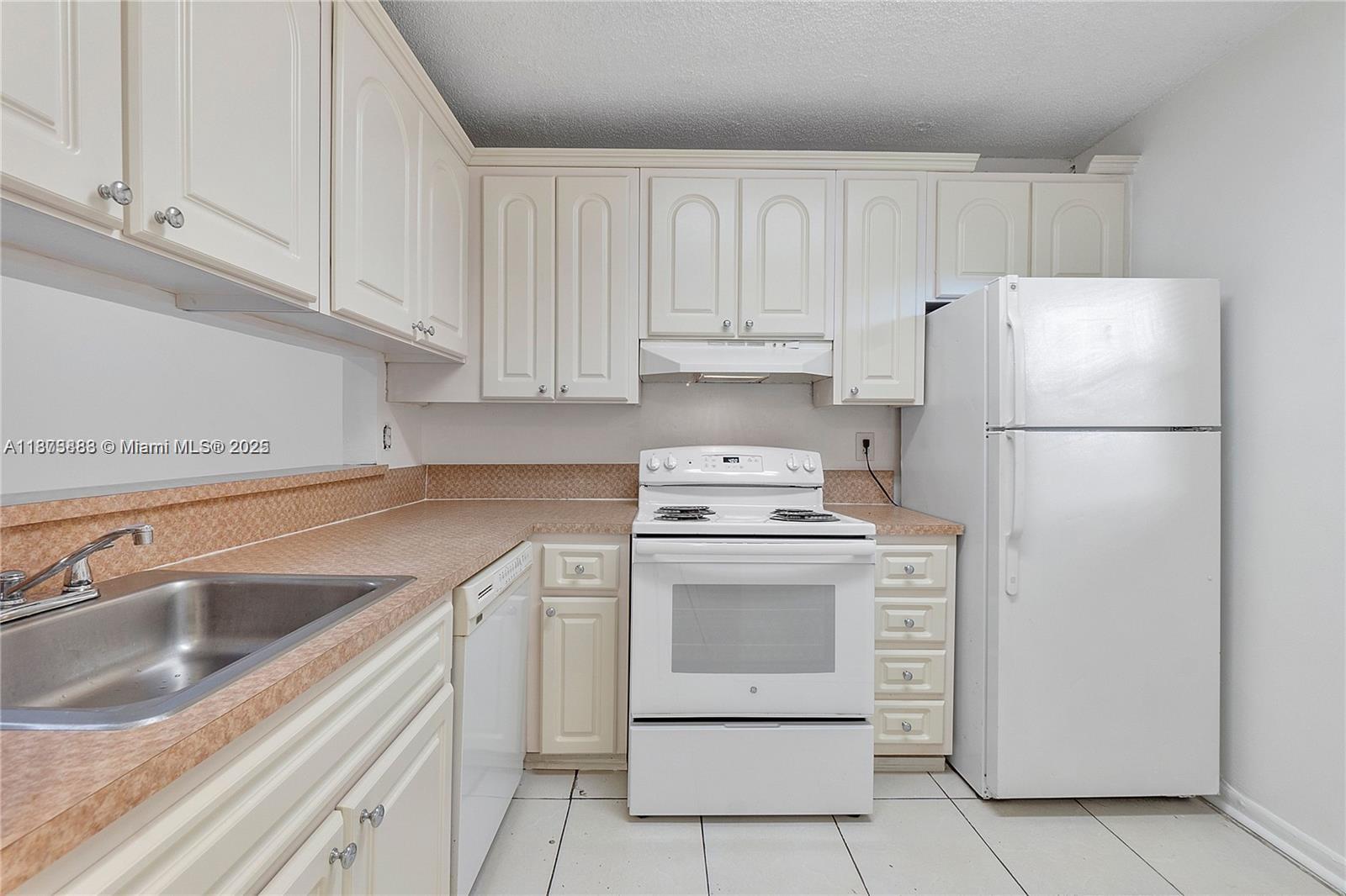 3399 Foxcroft Road, Unit 108 Miramar, FL 33025 - Photo 11 of 15 a kitchen with white cabinets and white appliances