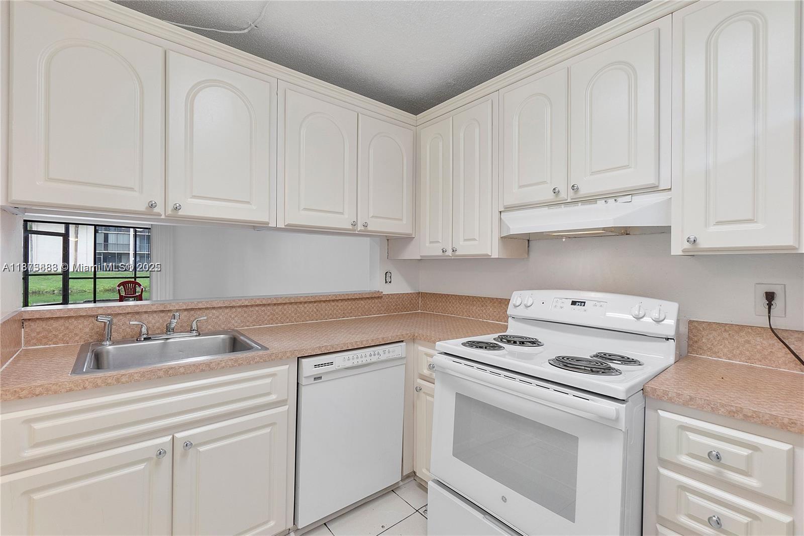 3399 Foxcroft Road, Unit 108 Miramar, FL 33025 - Photo 10 of 15 a kitchen with white cabinets and white appliances