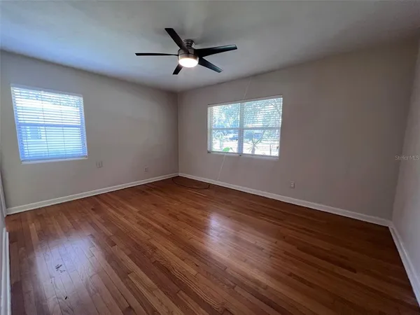 a view of an empty room with wooden floor and a window