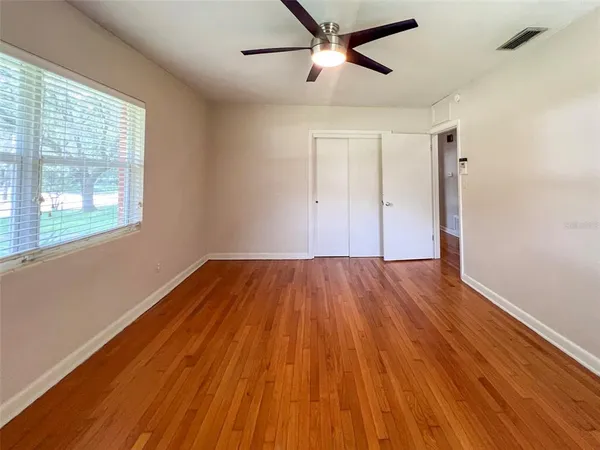 a view of empty room with wooden floor and fan