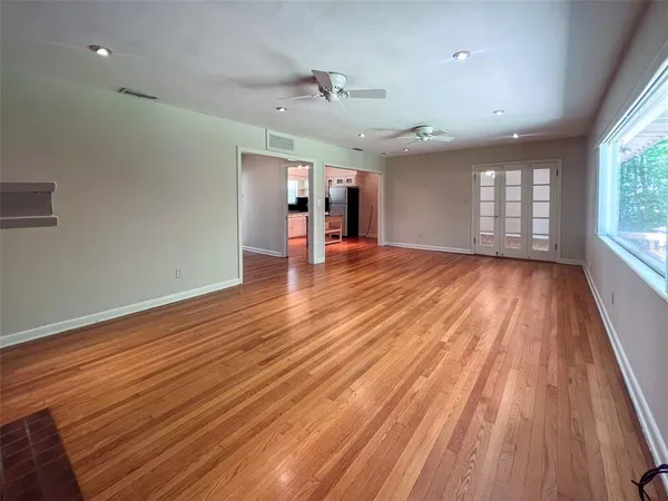 an empty room with wooden floor and windows