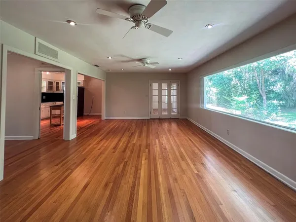 an empty room with wooden floor and windows