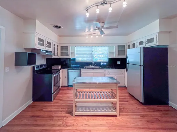 a view of a kitchen with stainless steel appliances granite countertop a stove a refrigerator and a wooden cabinets