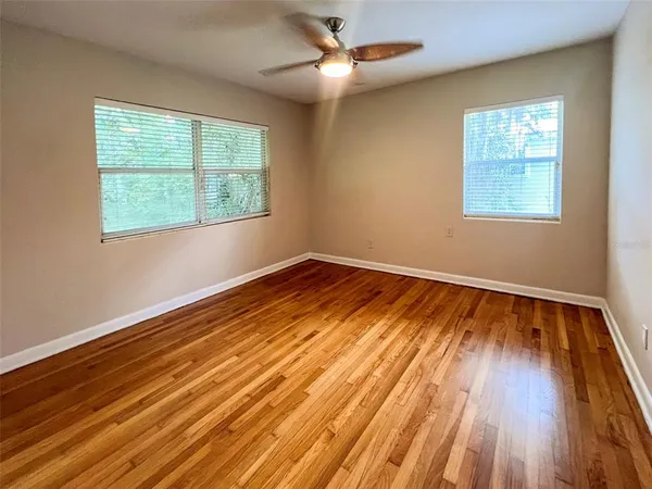a view of empty room with wooden floor and fan