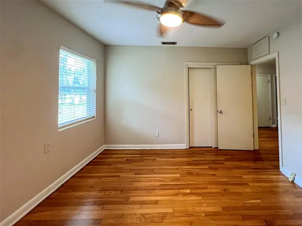 an empty room with wooden floor fan and windows