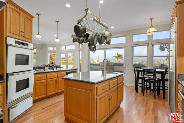 a kitchen with stainless steel appliances granite countertop a stove and chairs with wooden floors
