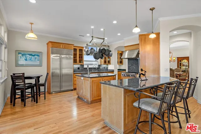 a kitchen with stainless steel appliances kitchen island granite countertop a table chairs and a refrigerator
