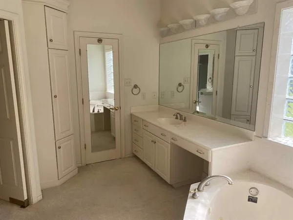 a spacious bathroom with a tub sink and mirror