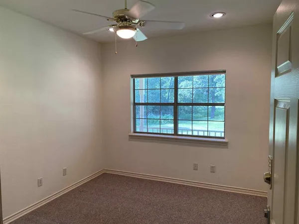an empty room with a window and a fan