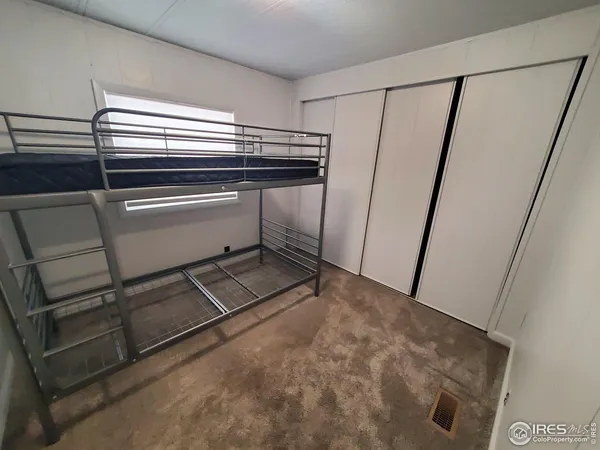 a refrigerator in kitchen and an empty room