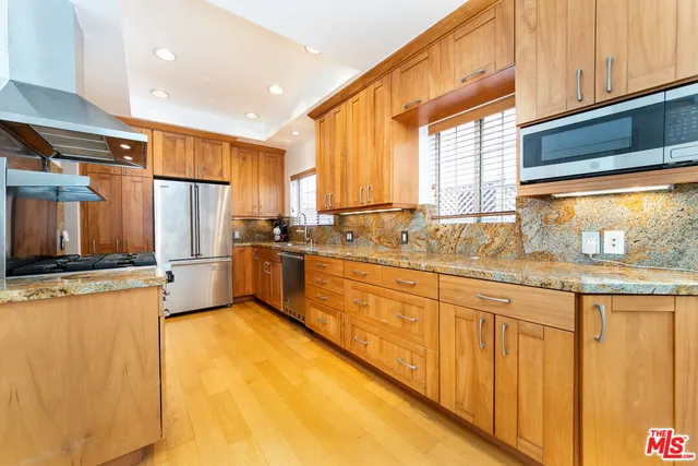 a kitchen with granite countertop a sink a counter top space and stainless steel appliances