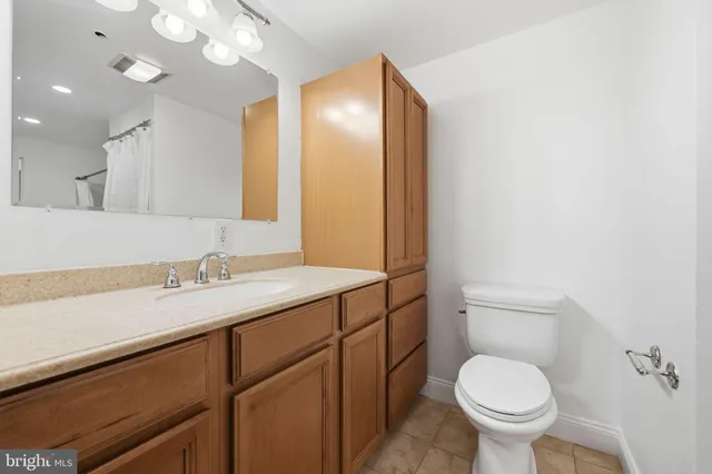 a bathroom with a granite countertop sink toilet and mirror