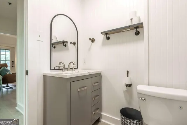 a bathroom with a granite countertop sink a toilet and a mirror