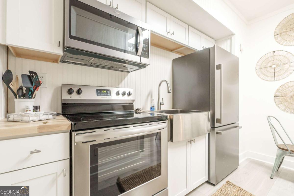 1413 2nd Avenue, Unit 4 Tybee Island, GA 31328 - Photo 22 of 32 a kitchen with stainless steel appliances granite countertop a stove and a refrigerator