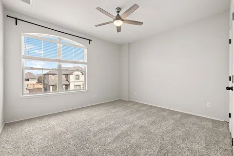 an empty room with a window and a fan