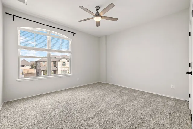 an empty room with a window and a fan