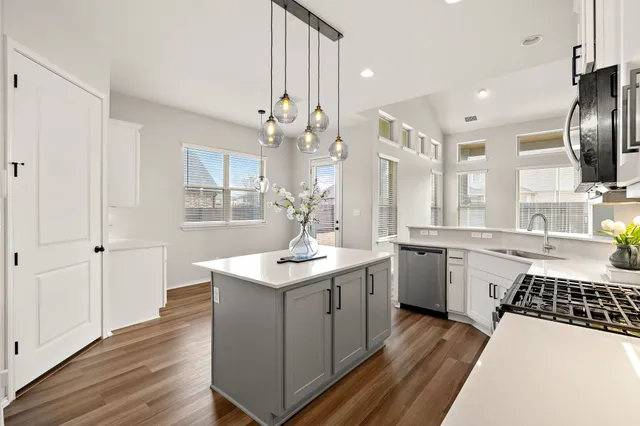 a kitchen with a sink a stove a refrigerator and white cabinets