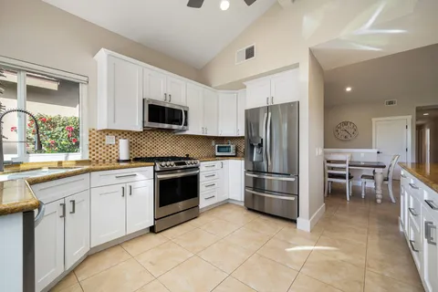 a kitchen with granite countertop a refrigerator stove top oven and sink