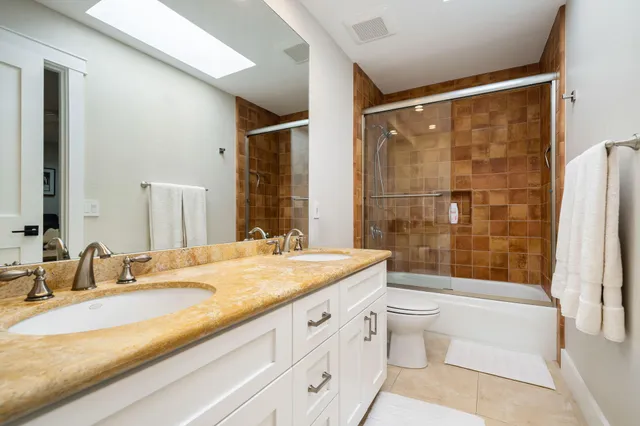 a bathroom with a granite countertop sink a toilet a mirror and shower