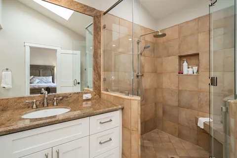 a bathroom with a granite countertop sink a mirror and shower