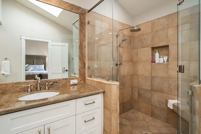 a bathroom with a granite countertop sink a mirror and shower