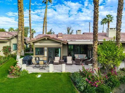 a view of a patio with table and chairs potted plants and palm tree
