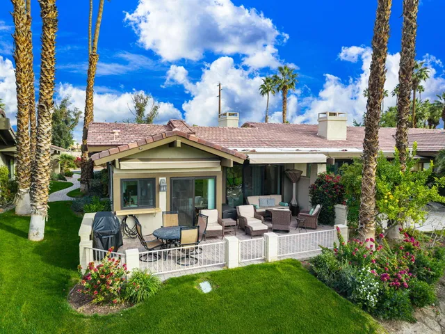 a view of a patio with table and chairs potted plants and a large tree